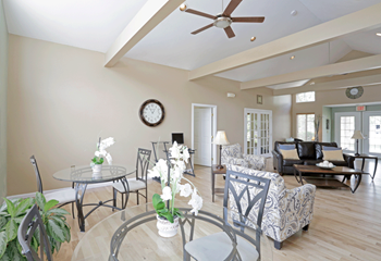 a living room with a ceiling fan and a round glass table with chairs